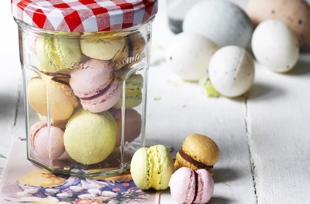 Jar of pastel macarons with a red checkered lid on white painted wood