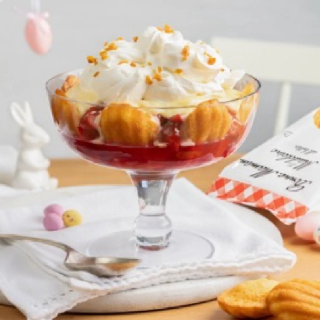 Stemmed glass dessert with red compote, madeleines, whipped cream, and pastel eggs