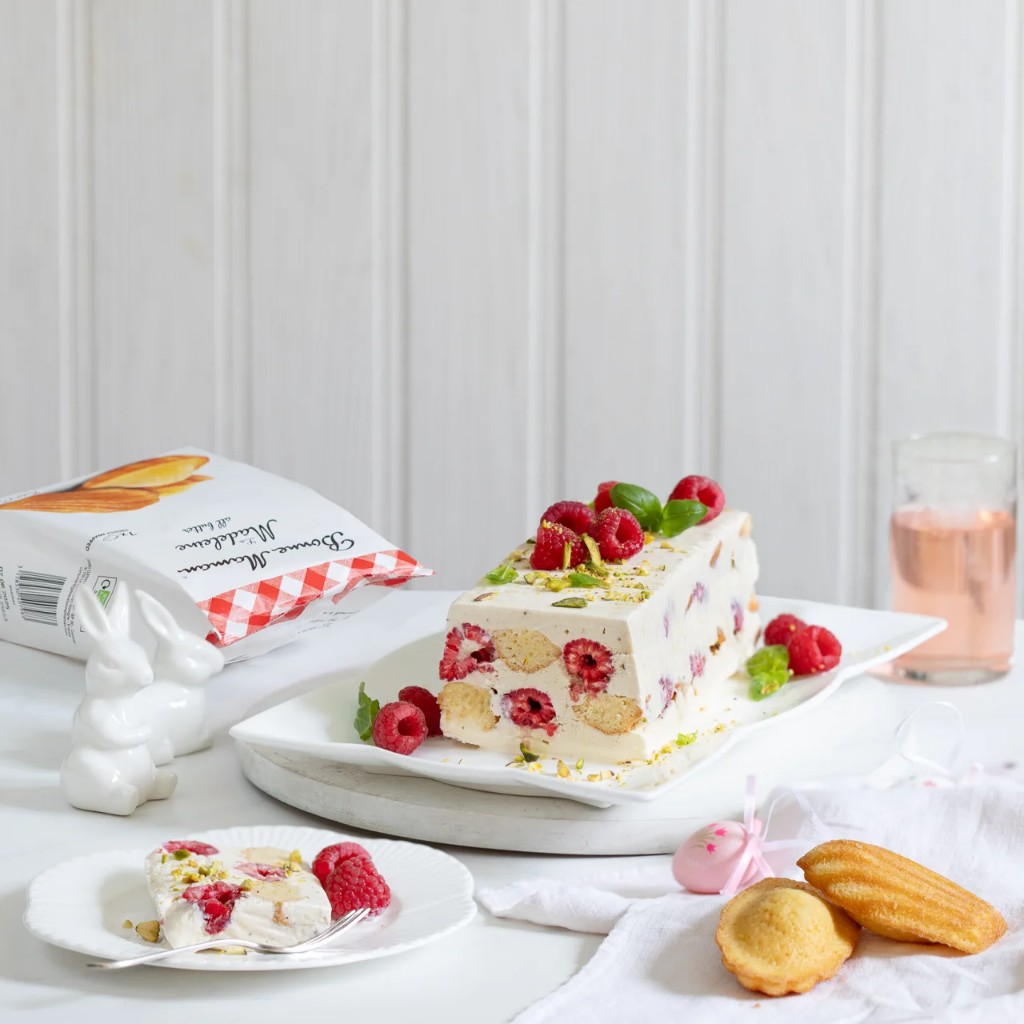 Raspberry pistachio semifreddo loaf with slice, madeleine bag, and spring props